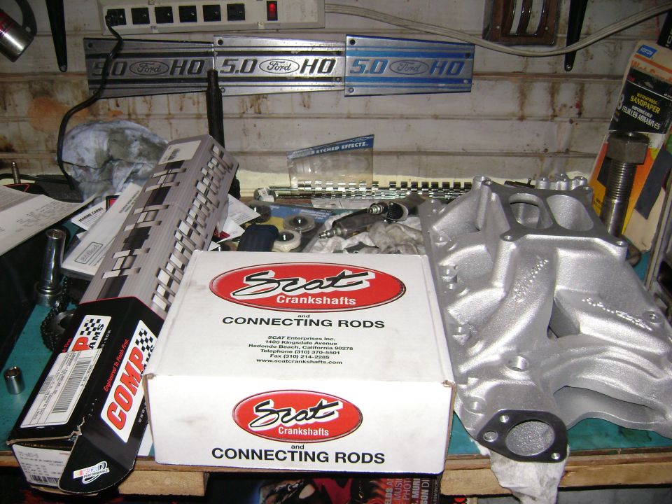 Silver aluminum intake manifold and boxes of Scat connecting rods on a workbench