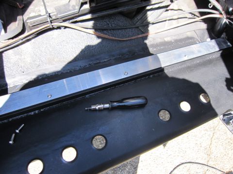 1996 Ford Bronco - A screwdriver and screws are visible on the black interior trim of a vehicle.