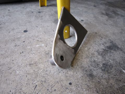 1996 Ford Bronco - A close-up view of a metal bracket with two holes, placed on a concrete surface.