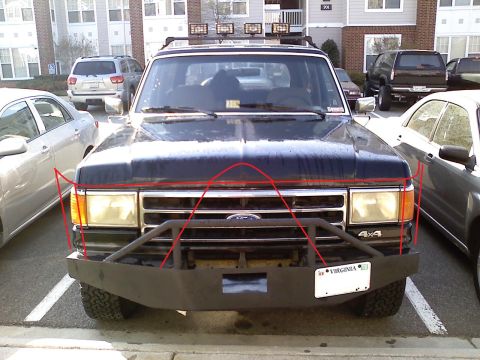 1990 Ford Bronco - Head-on view of a dark blue Ford full-size 4x4 SUV parked between cars in an apartment lot, wearing a fabricated flat-plate front bumper wi…