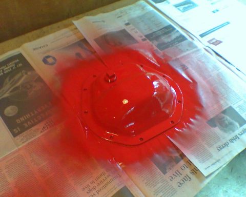 1987 Ford Bronco - Differential cover painted red, placed on newspaper.