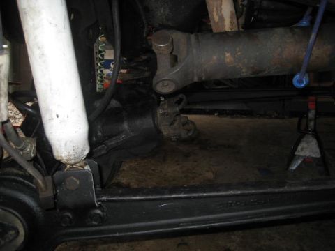 1987 Ford Bronco - Undercarriage view of a vehicle's suspension and drivetrain components, possibly undergoing maintenance.