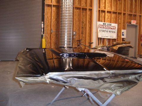 1973 Ford Ranchero - A car hood is covered in plastic sheeting and resting on a stand in a workshop environment.