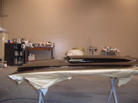 1973 Ford Ranchero - Car hood undergoing paint preparation in a workshop setting with various supplies visible.