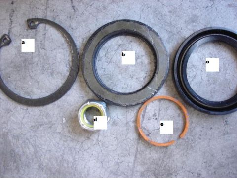 1992 Ford Bronco - Several automotive parts, including seals and a snap ring, are arranged on a textured surface.