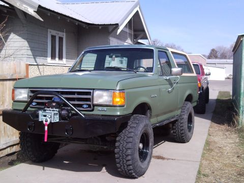 1989 Ford Bronco - This 1989 Ford Bronco features a custom front bumper with a winch, and is parked alongside another vehicle.