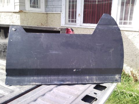 1989 Ford Bronco - A black plastic panel, possibly a fender or trim piece, is shown resting on a truck bed, with a red taillight visible in the background.
