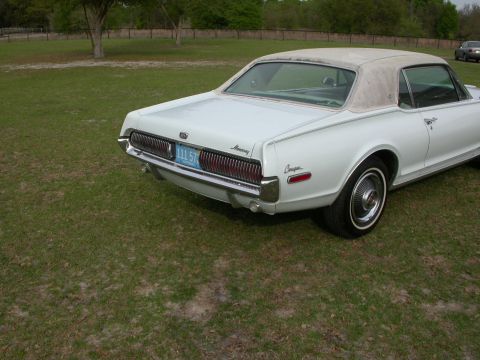1968 Mercury Cougar - A white 1968 Mercury Cougar is parked on a grassy area with trees in the background.