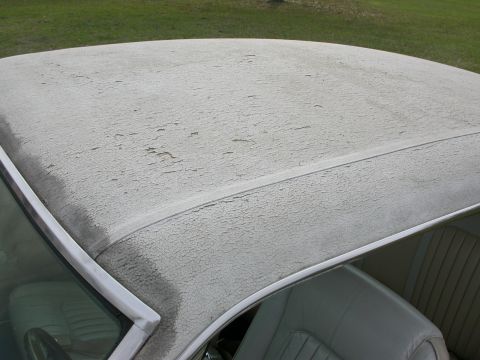 1968 Mercury Cougar - The white vinyl top of a car shows significant paint deterioration and cracking.