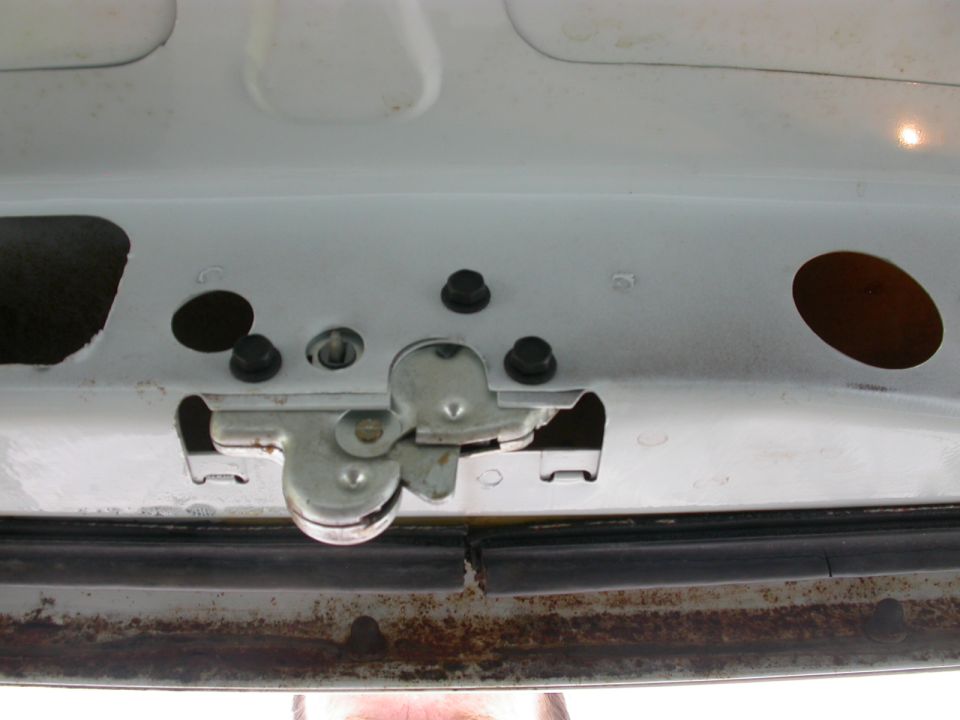 Close-up of a car's trunk latch mechanism. Shows metal parts and some rust