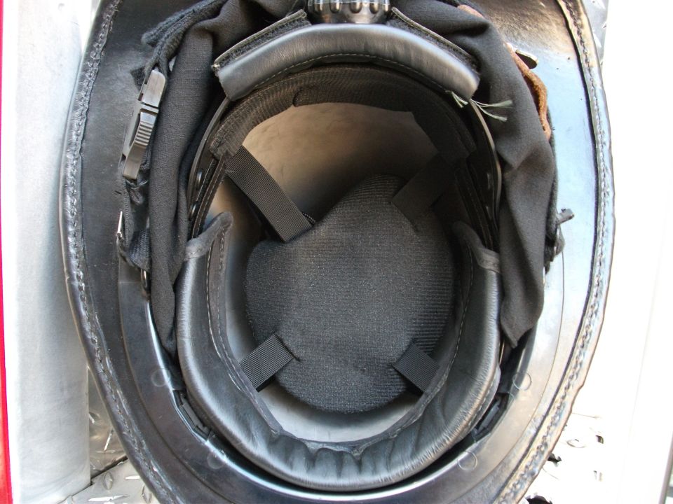 Inside of a black helmet showing padded liner and straps on a diamond-plate surface