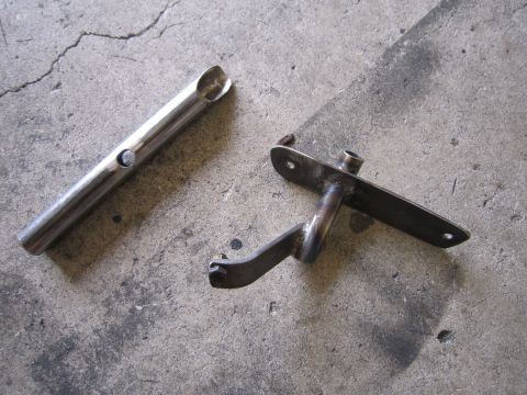 1996 Ford Bronco - Two metal automotive parts are shown on a concrete floor, possibly for a vehicle repair or modification.