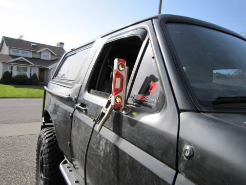 1996 Ford Bronco - A dark gray Ford Bronco is shown from the side, with a level clamped to the door and a sticker on the window.
