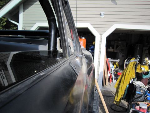 1996 Ford Bronco - Close-up of a black SUV's side door and window, with a garage visible behind it.