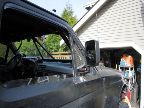 1996 Ford Bronco - The side mirror and interior of a dark gray Ford Bronco are visible.