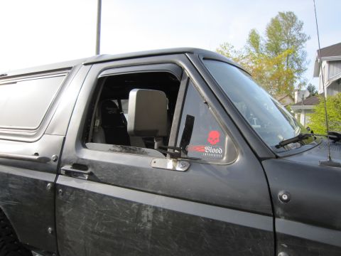 1996 Ford Bronco - Side view of a black SUV, a red skull sticker on the window and a visible interior.