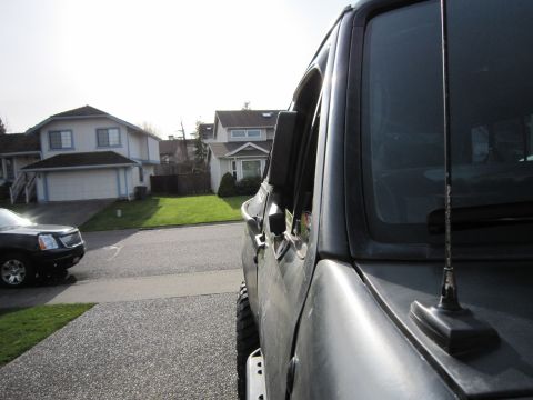 1996 Ford Bronco - Side view of a dark SUV, with another vehicle parked across the street.