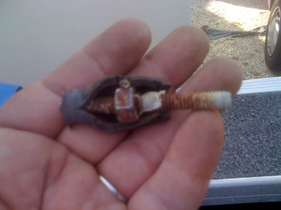 Hand holding a rusty trolling motor part with a threaded shaft