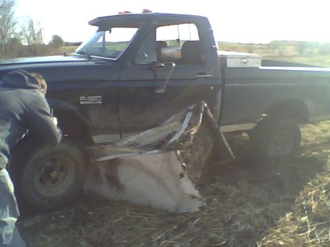 1995 Ford F-150 - A person inspects the damaged front passenger side of a black Ford F-150 truck.
