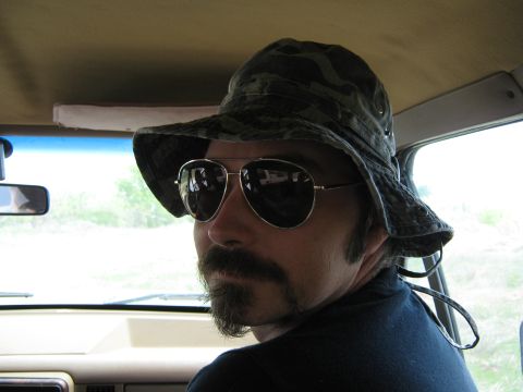 Man wearing camouflage bucket hat and aviator sunglasses inside a vehicle