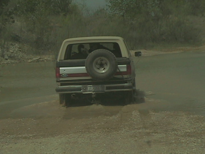 Ford Bronco driving through water, spare tire on back
