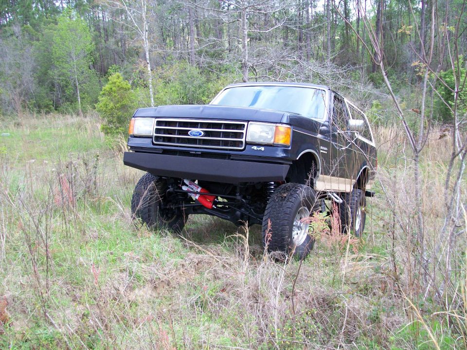 Black lifted Ford Bronco on tall suspension in a field