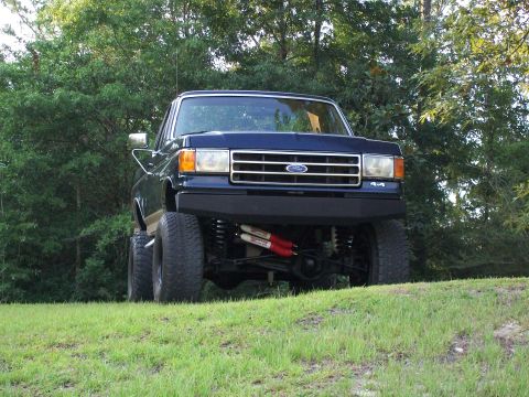 1990 Ford Bronco - This lifted Ford truck features a prominent grille and 4x4 badging, suggesting a model year in the late 1980s.