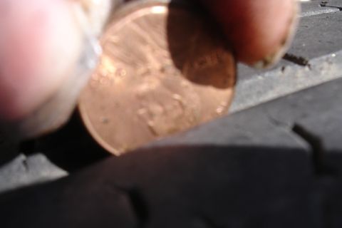 1993 Ford Taurus - A penny is placed on the tread of a tire, obscuring some of the detail.