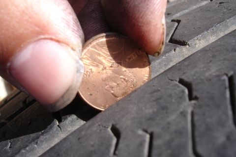1993 Ford Taurus - Penny inserted into tire tread to gauge depth, revealing the year 2000 on the coin.