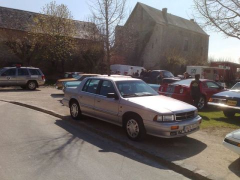 1991 Ford Crown Victoria - A silver sedan is parked on the side of the road with other vehicles in the background.