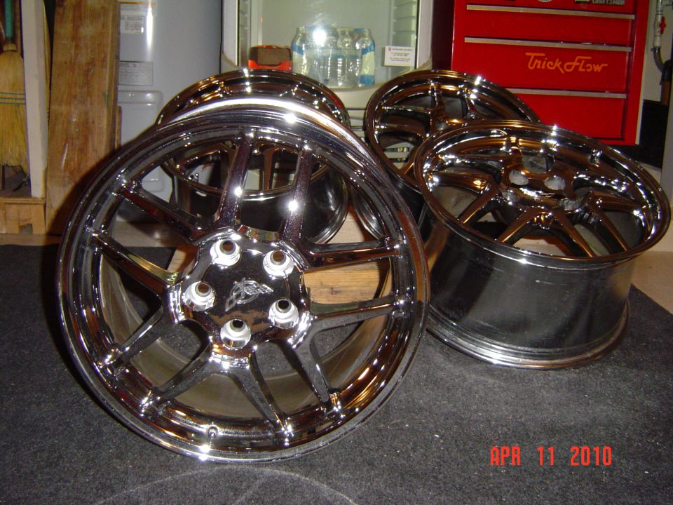 Two chrome split-spoke wheels in a garage