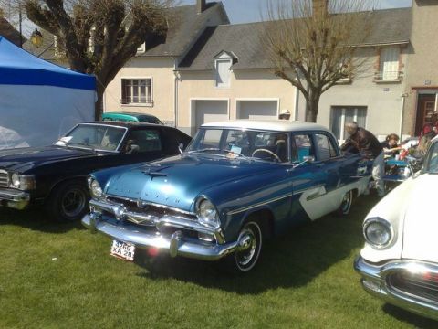 1991 Ford Crown Victoria - A classic 1955 Plymouth sedan, painted in a striking blue and white two-tone, is displayed at an outdoor car show.