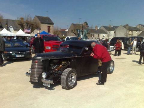 1991 Ford Crown Victoria - A black hot rod is on display with several other vehicles and people in the background.