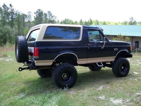 1990 Ford Bronco - This lifted Ford Bronco features a two-tone paint scheme and a rear-mounted spare tire.