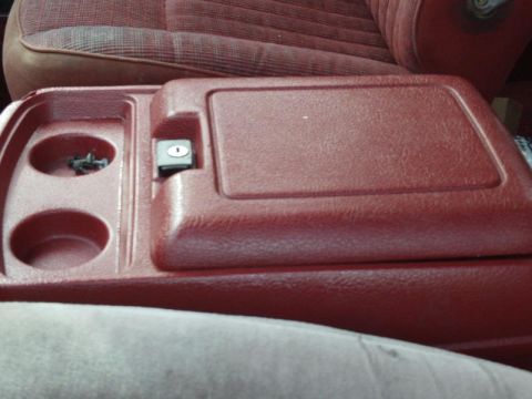 1988 Ford Bronco - Interior view of a red console with cup holders and a lockable armrest, consistent with a 1988 Ford Bronco.