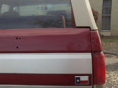 1988 Ford Bronco - Rear view of a two-tone red and silver 1988 Ford Bronco, a Texas flag emblem on the tailgate.