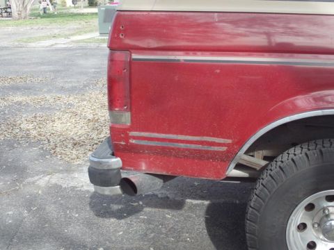 1988 Ford Bronco - Rear view of a red SUV, showing its quarter panel, taillight, and exhaust pipe.