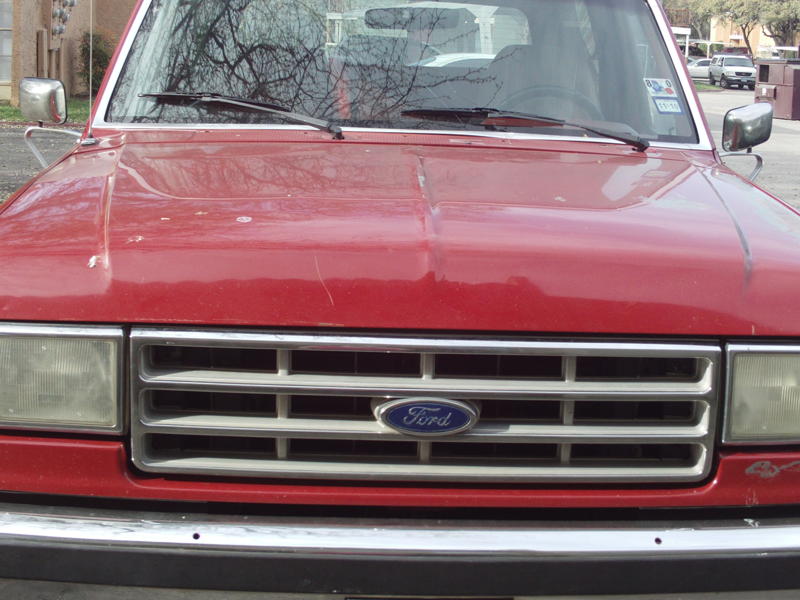 Red Ford Bronco front grille with Ford logo, showing rectangular headlights and chrome bumper