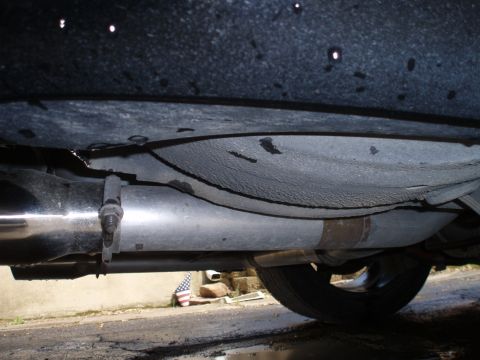 2002 Chevrolet Camaro - A close-up view of the exhaust system and undercarriage of a vehicle, with a tire visible.