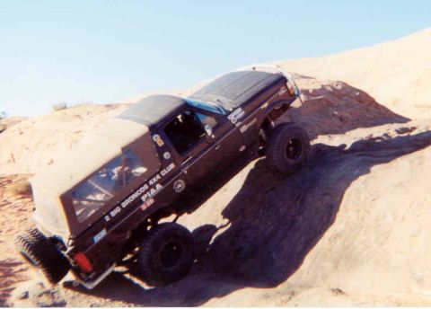 2002 Ford F-350 - A modified Ford Bronco navigates a steep, sandy incline during an off-road excursion.