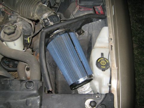 2000 Mercury Grand Marquis - Close-up of an engine bay with an aftermarket air filter and various hoses and fluid reservoirs.