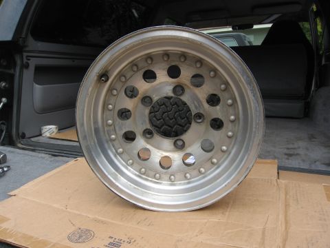1986 Ford Bronco - An aluminum wheel is shown in the cargo area of a vehicle.