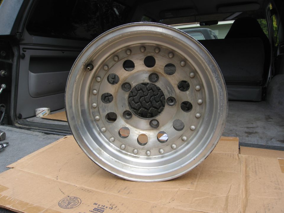 Aluminum wheel with multiple holes and a tire tread visible through the center