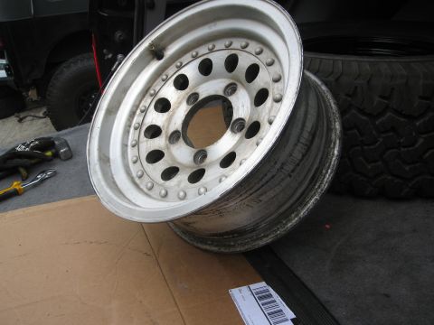 1986 Ford Bronco - An aluminum wheel and tire are shown, with tools and part of a vehicle in the background.