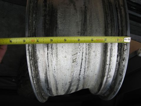 1986 Ford Bronco - A close-up view of a dirty aluminum wheel rim being measured with a tape measure.
