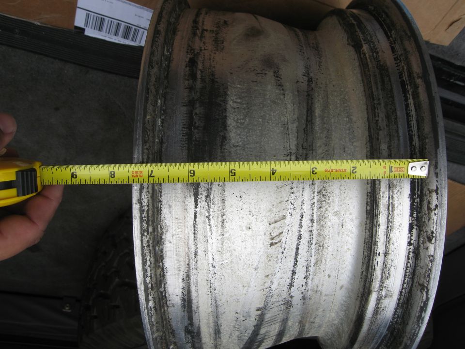 Measuring the width of a wheel rim with a yellow tape measure