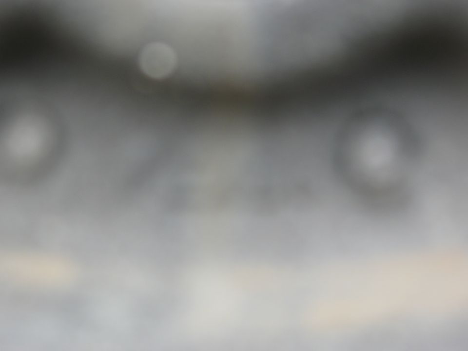 Blurred metallic part with circular indentations and a watermark