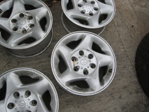 1986 Ford Bronco - These four alloy wheels feature the Toyota logo in the center and are shown resting on a concrete surface.