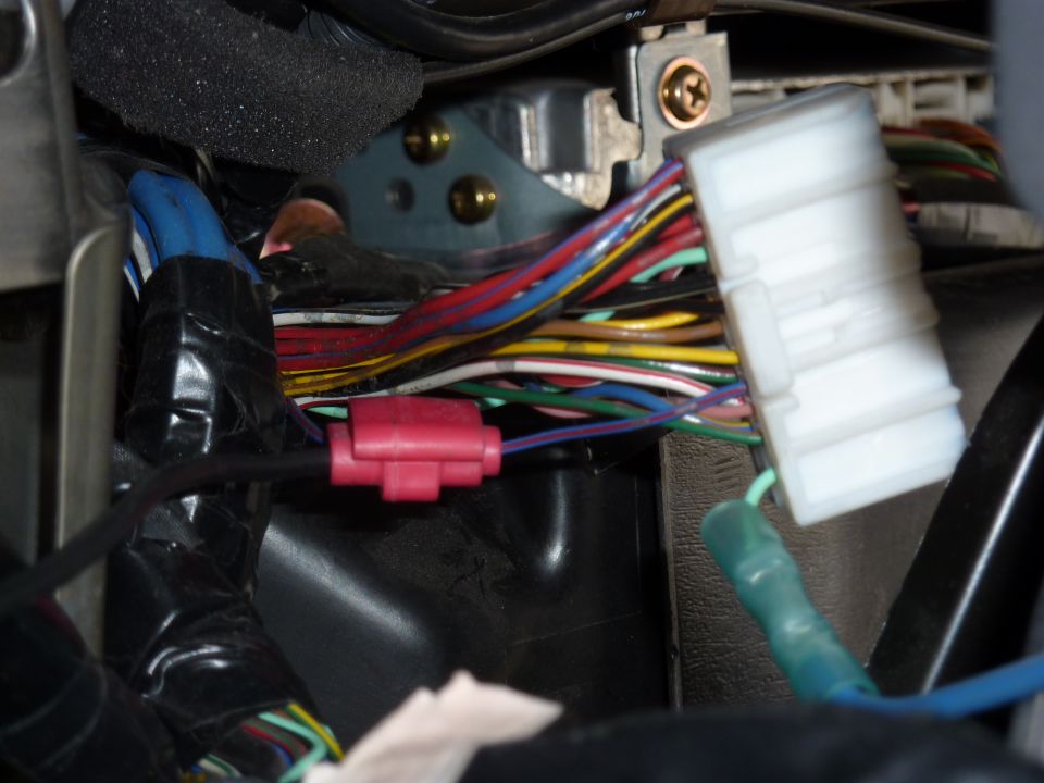 Close-up of dash wiring harness with white connector and red crimp splice