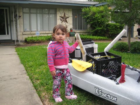 1953 Ford Mainline - A young child stands beside a kayak equipped with PVC pipe holders, ready for an outdoor adventure.